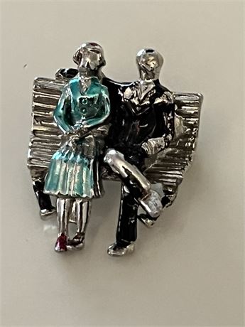 Man and woman sitting on a bench, silver metal brooch